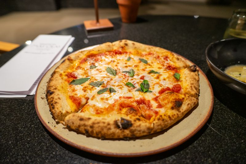 Jet's pizza wood-fired specialty pizza coming out of the stone oven